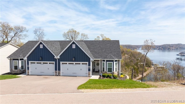 23 Enclaves Ln, Lake Ozark, MO 65049 - view of front of house with board and batten siding, driveway, an attached garage, a front yard, and a water view