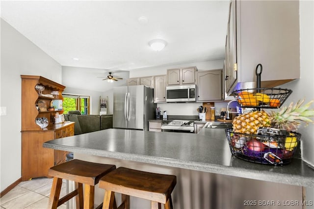 180 Skylark Ln, Linn Creek, MO 65052 - kitchen featuring appliances with stainless steel finishes, a peninsula, ceiling fan, light tile patterned flooring, and a breakfast bar area