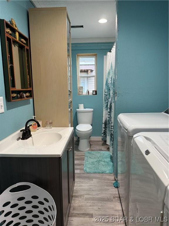 58 Aztec Ln, Eldon, MO 65026 - full bath featuring washing machine and clothes dryer, vanity, wood finished floors, and a shower with shower curtain