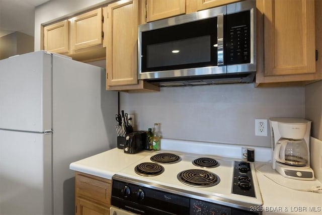 33 Monterey Dr Unit 2A, Lake Ozark, MO 65049 - kitchen with stainless steel microwave, freestanding refrigerator, stove, light countertops, and light brown cabinetry