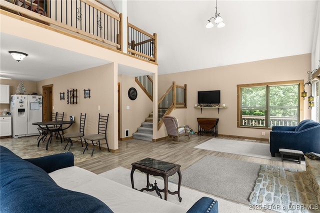 28 Hamilton Way, Sunrise Beach, MO 65079 - living room featuring a towering ceiling, stairway, light wood-style floors, and a chandelier