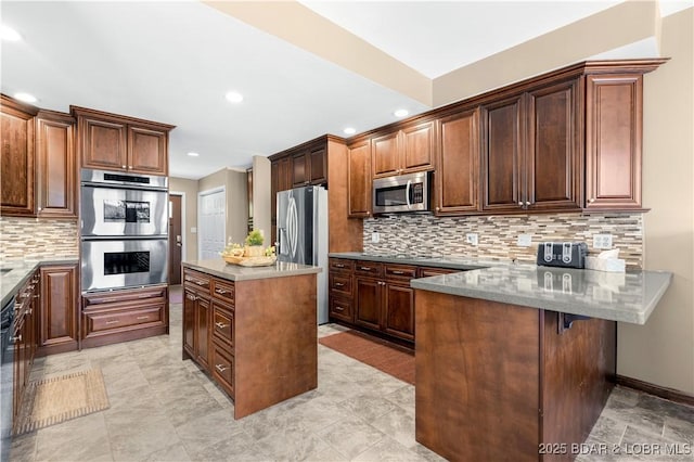 164 Get A Way Ln, Camdenton, MO 65020 - kitchen featuring appliances with stainless steel finishes, a kitchen island, tasteful backsplash, recessed lighting, and a peninsula
