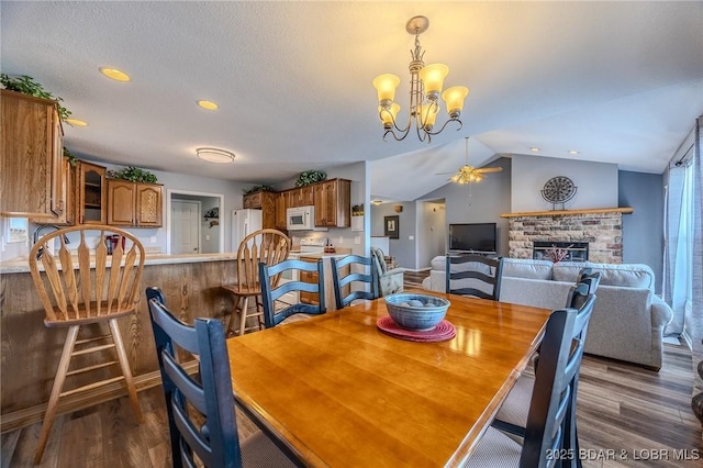 1508 Purvis Rd, Sunrise Beach, MO 65079 - dining space featuring dark wood-type flooring, a brick fireplace, ceiling fan, recessed lighting, and vaulted ceiling