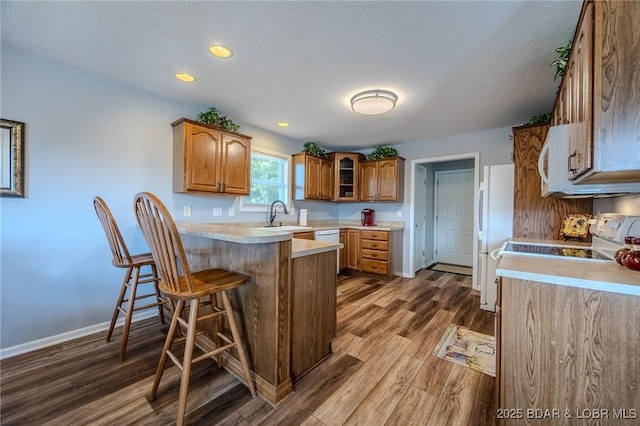 1508 Purvis Rd, Sunrise Beach, MO 65079 - kitchen with a peninsula, wood finished floors, brown cabinets, a kitchen bar, and light countertops