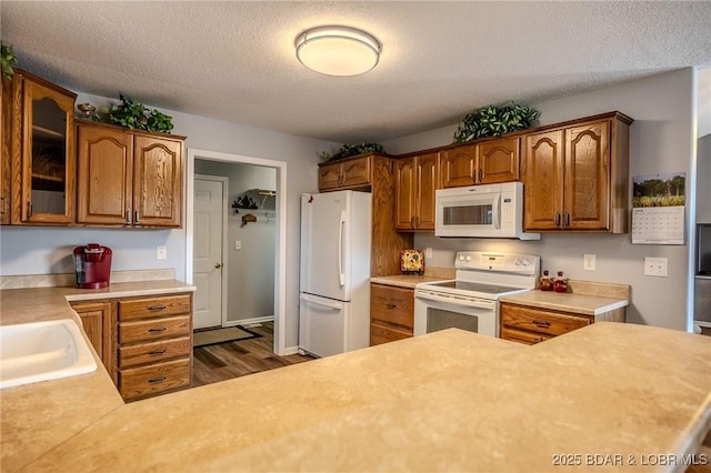 1508 Purvis Rd, Sunrise Beach, MO 65079 - kitchen with white appliances, dark wood finished floors, glass insert cabinets, a textured ceiling, and light countertops
