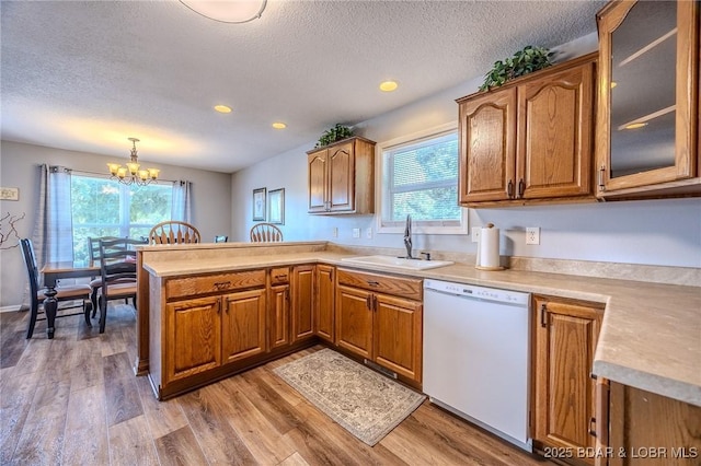 1508 Purvis Rd, Sunrise Beach, MO 65079 - kitchen featuring dishwasher, a peninsula, brown cabinetry, light wood-style flooring, and a textured ceiling