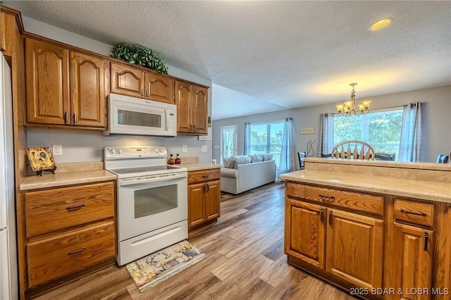 1508 Purvis Rd, Sunrise Beach, MO 65079 - kitchen with white appliances, brown cabinets, light countertops, a textured ceiling, and a chandelier