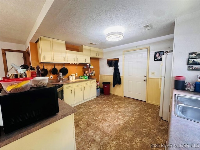 25372 Loon Blvd, Warsaw, MO 65355 - kitchen featuring black microwave, freestanding refrigerator, a textured ceiling, and cream cabinetry