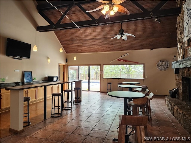 5940 Baydy Peak Rd Unit 1232, Osage Beach, MO 65065 - dining room with ceiling fan, a wooden ceiling with exposed beams, high vaulted ceiling, a stone fireplace, and dark tile patterned flooring