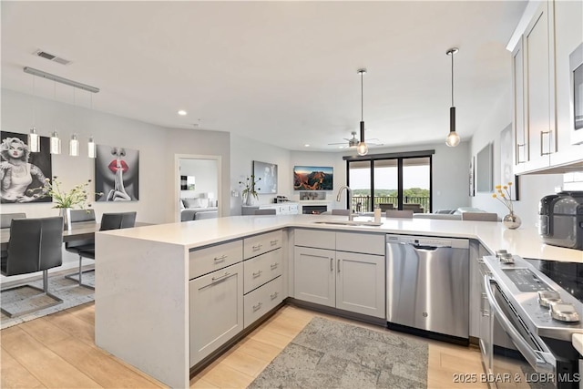 166 Captiva Dr Unit 5D, Sunrise Beach, MO 65079 - kitchen with appliances with stainless steel finishes, open floor plan, light countertops, a peninsula, and decorative light fixtures