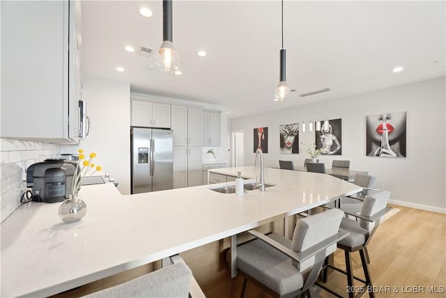166 Captiva Dr Unit 5D, Sunrise Beach, MO 65079 - kitchen featuring appliances with stainless steel finishes, a peninsula, backsplash, light countertops, and a breakfast bar area