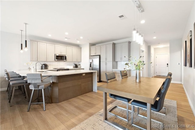 166 Captiva Dr Unit 5D, Sunrise Beach, MO 65079 - kitchen featuring appliances with stainless steel finishes, a peninsula, backsplash, light countertops, and a kitchen breakfast bar
