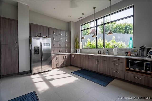 166 Captiva Dr Unit 5D, Sunrise Beach, MO 65079 - kitchen with stainless steel fridge, black microwave, backsplash, light countertops, and pendant lighting
