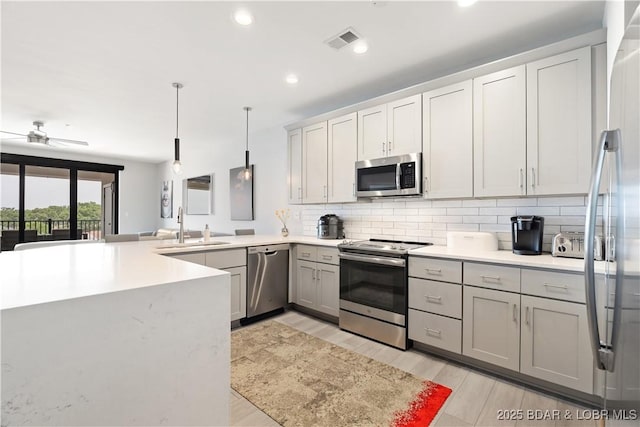 166 Captiva Dr Unit 5D, Sunrise Beach, MO 65079 - kitchen with stainless steel appliances, gray cabinetry, a peninsula, tasteful backsplash, and light countertops