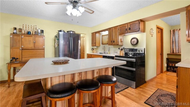 87 Outback Loop, Linn Creek, MO 65052 - kitchen featuring stainless steel appliances, a ceiling fan, a textured ceiling, light wood finished floors, and light countertops