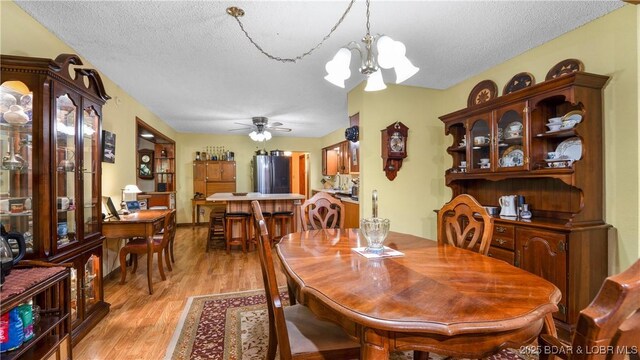 87 Outback Loop, Linn Creek, MO 65052 - dining space featuring light wood-style flooring, a chandelier, a textured ceiling, and ceiling fan