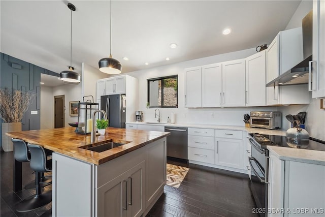 626 Eagle Dr, Four Seasons, MO 65049 - kitchen featuring stainless steel appliances, wooden counters, wall chimney range hood, dark wood-type flooring, and a center island with sink