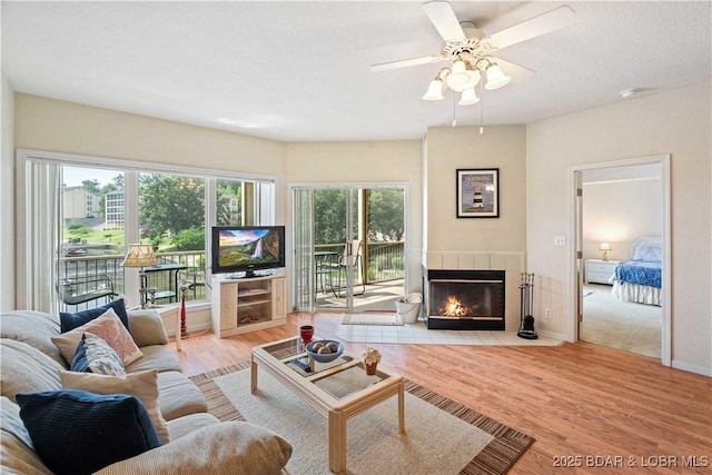 34 Bristol Bay Dr Unit 1C, Lake Ozark, MO 65049 - living room featuring a tiled fireplace, light wood-style flooring, and a ceiling fan