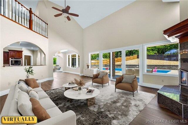 82 Fawn Meadows Dr, Linn Creek, MO 65052 - living area featuring arched walkways, high vaulted ceiling, a ceiling fan, and wood finished floors