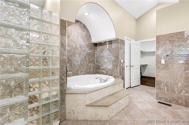 82 Fawn Meadows Dr, Linn Creek, MO 65052 - bathroom featuring a garden tub, tile walls, a walk in shower, tile patterned floors, and a spacious closet