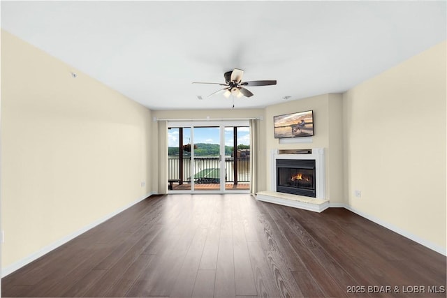 238 Cedar Glen Dr Unit 3F, Camdenton, MO 65020 - unfurnished living room featuring a warm lit fireplace, a ceiling fan, dark wood-type flooring, and a water view