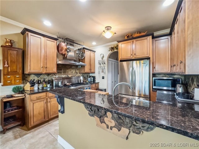 172 Highland Pkwy, Camdenton, MO 65020 - kitchen featuring appliances with stainless steel finishes, crown molding, wall chimney range hood, tasteful backsplash, and dark stone countertops