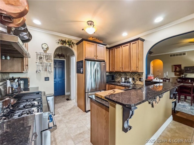 172 Highland Pkwy, Camdenton, MO 65020 - kitchen featuring arched walkways, appliances with stainless steel finishes, crown molding, backsplash, and a peninsula
