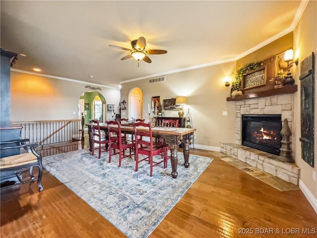 172 Highland Pkwy, Camdenton, MO 65020 - dining area featuring ceiling fan, arched walkways, crown molding, a fireplace, and wood finished floors