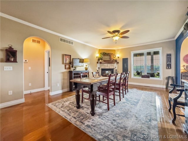 172 Highland Pkwy, Camdenton, MO 65020 - dining space featuring arched walkways, ceiling fan, wood finished floors, crown molding, and a fireplace