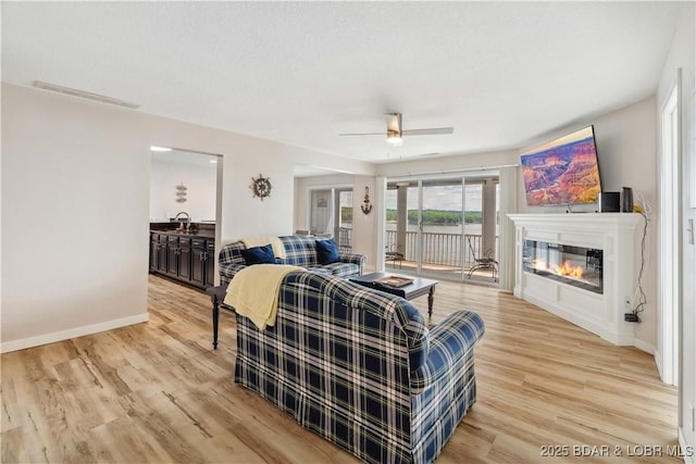 320 Regatta Bay Cir Unit 3B, Lake Ozark, MO 65049 - living area with light wood-style flooring, ceiling fan, and a glass covered fireplace