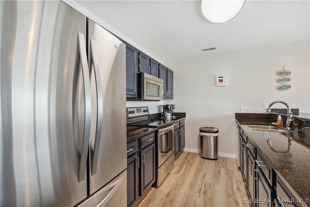 320 Regatta Bay Cir Unit 3B, Lake Ozark, MO 65049 - kitchen featuring appliances with stainless steel finishes, dark stone countertops, a textured ceiling, and light wood-style flooring