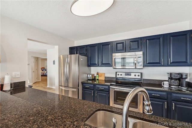 320 Regatta Bay Cir Unit 3B, Lake Ozark, MO 65049 - kitchen featuring appliances with stainless steel finishes, tasteful backsplash, blue cabinetry, a textured ceiling, and dark stone counters