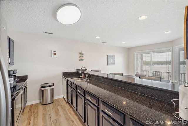 320 Regatta Bay Cir Unit 3B, Lake Ozark, MO 65049 - kitchen with stainless steel appliances, a textured ceiling, light wood-style floors, dark stone counters, and recessed lighting