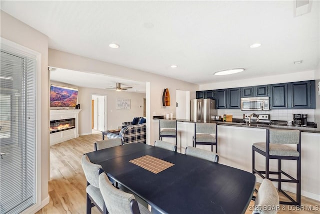 320 Regatta Bay Cir Unit 3B, Lake Ozark, MO 65049 - dining space featuring a glass covered fireplace, light wood-style flooring, recessed lighting, and a ceiling fan