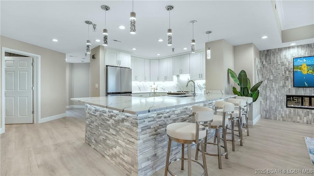 4800 Eagleview Dr Unit 8106, Osage Beach, MO 65065 - kitchen featuring stainless steel refrigerator, light wood-type flooring, light stone countertops, an accent wall, and a peninsula