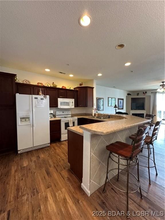 18134 Millstone Cove Rd Unit 212, Gravois Mills, MO 65037 - kitchen featuring white appliances, dark wood finished floors, a peninsula, dark brown cabinetry, and a breakfast bar area