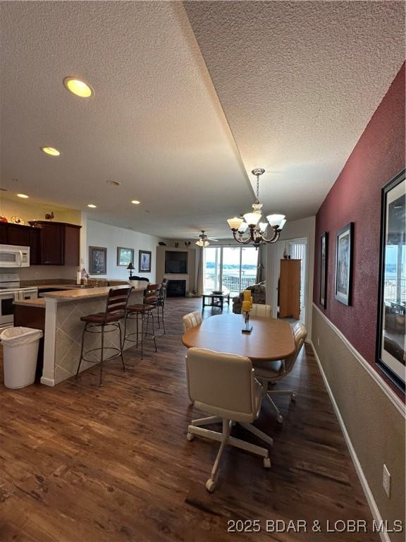 18134 Millstone Cove Rd Unit 212, Gravois Mills, MO 65037 - dining space featuring a textured ceiling, dark wood-type flooring, a chandelier, a textured wall, and ceiling fan