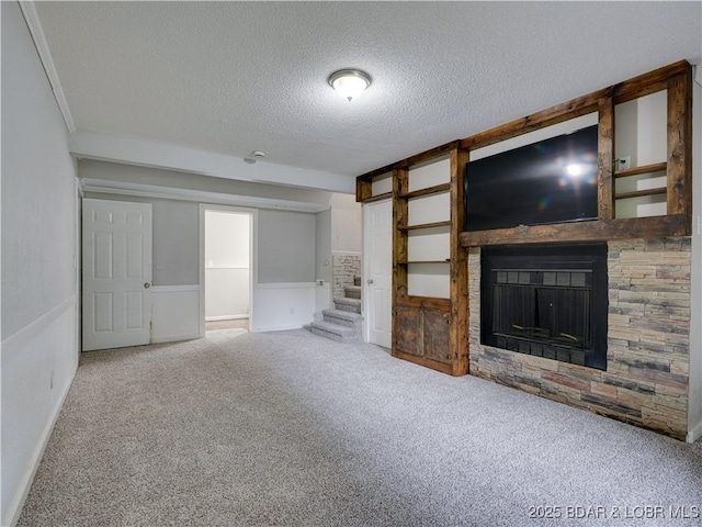 25 Primrose Ln, Camdenton, MO 65020 - unfurnished living room featuring a textured ceiling, carpet flooring, a fireplace, stairway, and wainscoting