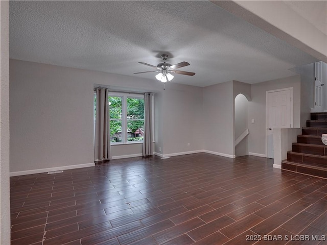 25 Primrose Ln, Camdenton, MO 65020 - unfurnished living room with arched walkways, ceiling fan, stairway, a textured ceiling, and dark wood-type flooring