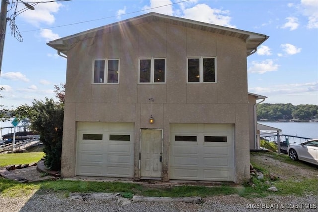 29773 Hemlock Rd, Gravois Mills, MO 65037 - rear view of property with a garage, stucco siding, and a water view