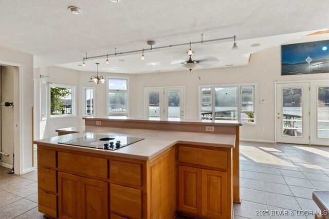 29773 Hemlock Rd, Gravois Mills, MO 65037 - kitchen featuring black electric cooktop, light tile patterned floors, light countertops, and a chandelier