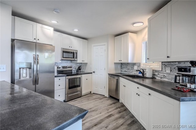 172 Kansas City Way, Sunrise Beach, MO 65079 - kitchen featuring stainless steel appliances, dark countertops, tasteful backsplash, light wood-style flooring, and white cabinets