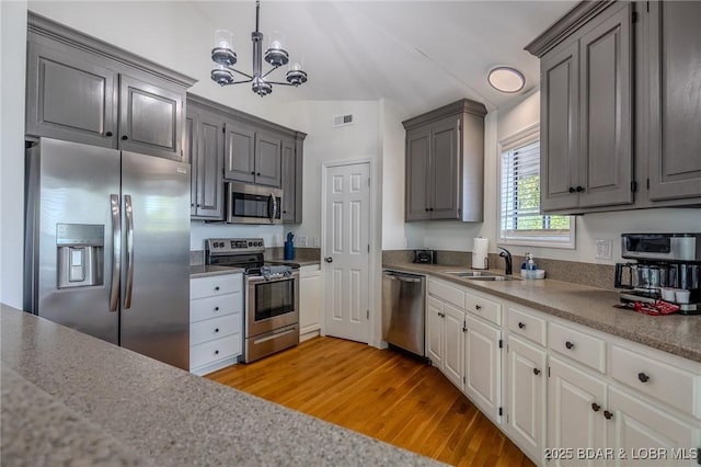 172 Kansas City Way, Sunrise Beach, MO 65079 - kitchen featuring stainless steel appliances, light wood-type flooring, a chandelier, gray cabinetry, and hanging light fixtures