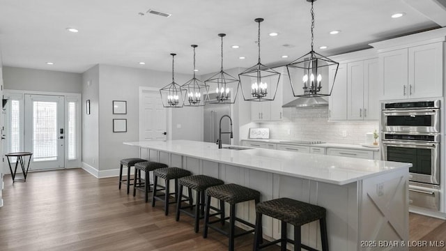 5450 Christopher Dr Unit 243, Osage Beach, MO 65065 - kitchen featuring stainless steel double oven, a chandelier, dark wood-style floors, a large island with sink, and recessed lighting