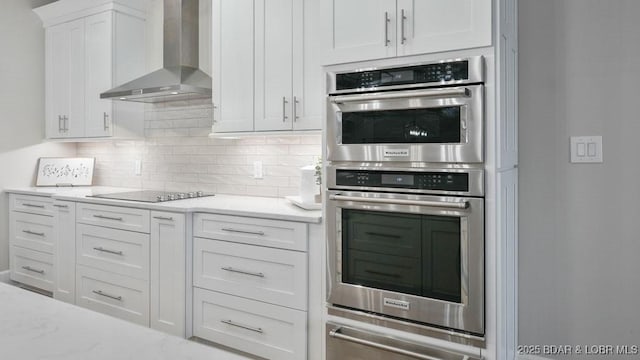 5450 Christopher Dr Unit 243, Osage Beach, MO 65065 - kitchen with wall chimney exhaust hood, stainless steel double oven, black electric cooktop, white cabinetry, and tasteful backsplash