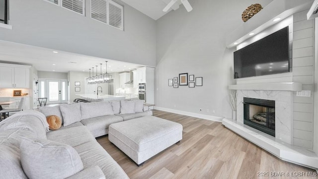 5450 Christopher Dr Unit 243, Osage Beach, MO 65065 - living room featuring light wood finished floors, a premium fireplace, a towering ceiling, and recessed lighting