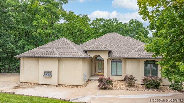 135 Greensboro Ct, Four Seasons, MO 65049 - french country home featuring stucco siding, a shingled roof, and driveway