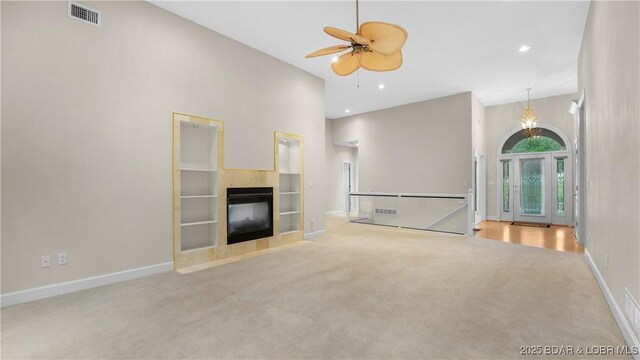 135 Greensboro Ct, Four Seasons, MO 65049 - unfurnished living room featuring carpet floors, ceiling fan, a tiled fireplace, a towering ceiling, and recessed lighting