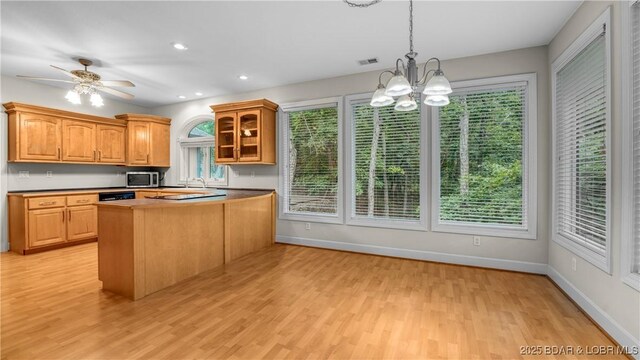 135 Greensboro Ct, Four Seasons, MO 65049 - kitchen featuring stainless steel microwave, light wood-style flooring, a chandelier, glass insert cabinets, and pendant lighting