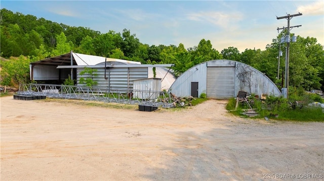 30383 Bullock Dr, Gravois Mills, MO 65037 - view of front of property featuring a pole building, dirt driveway, a detached garage, and an outbuilding